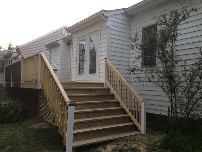 A white house with a wooden deck and stairs