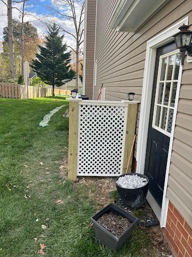 A house with a black door and a white lattice fence in front of it.