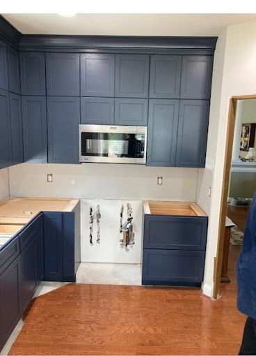 A kitchen with blue cabinets and a stainless steel microwave.