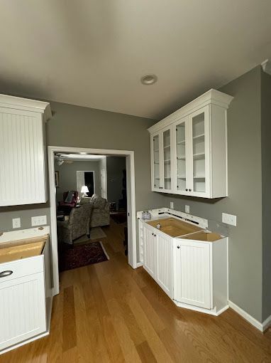A kitchen with white cabinets , hardwood floors , and a sink.