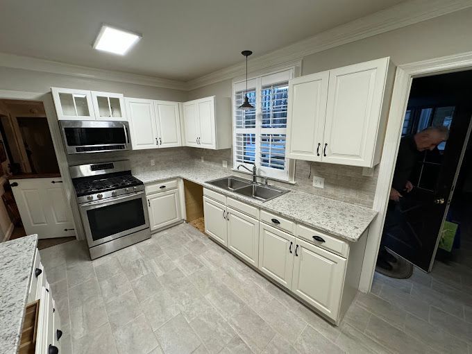 A kitchen with white cabinets , stainless steel appliances , granite counter tops and a sink.