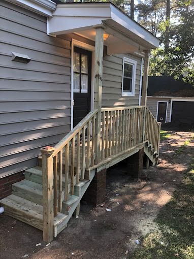 A wooden deck with stairs leading up to the front door of a house.