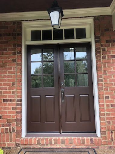 A brown double door is on a brick building.