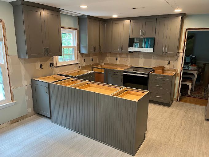 A kitchen is being remodeled with gray cabinets and a large island.