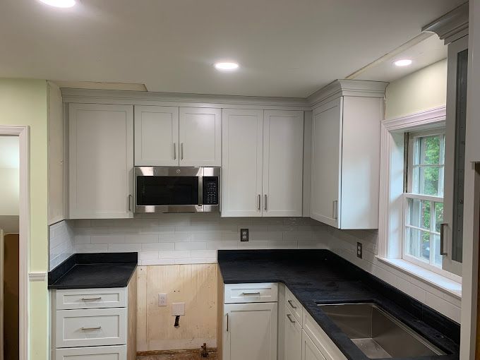 A kitchen with white cabinets and black counter tops