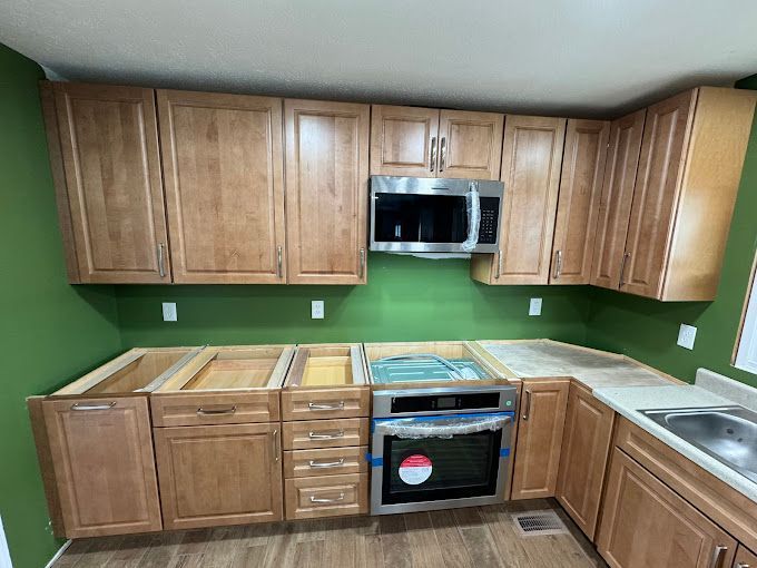 A kitchen with wooden cabinets , stainless steel appliances , and green walls.