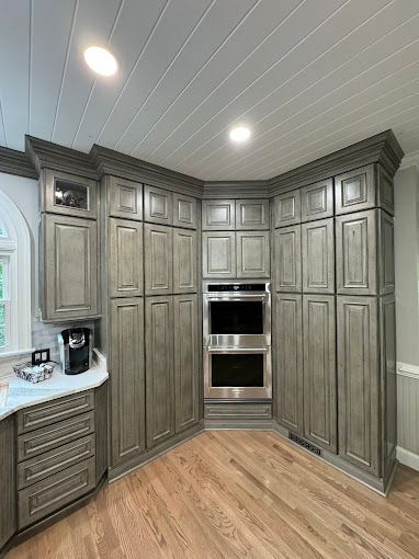 A kitchen with gray cabinets and a stainless steel oven.
