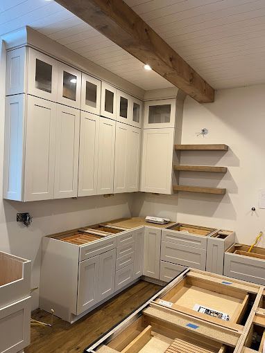 A kitchen under construction with white cabinets and wooden floors.