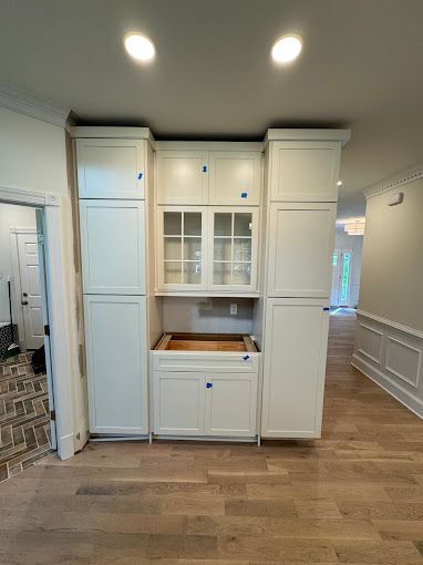 A kitchen with white cabinets and hardwood floors is being remodeled.