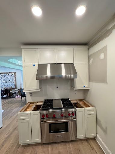A kitchen with stainless steel appliances and white cabinets.