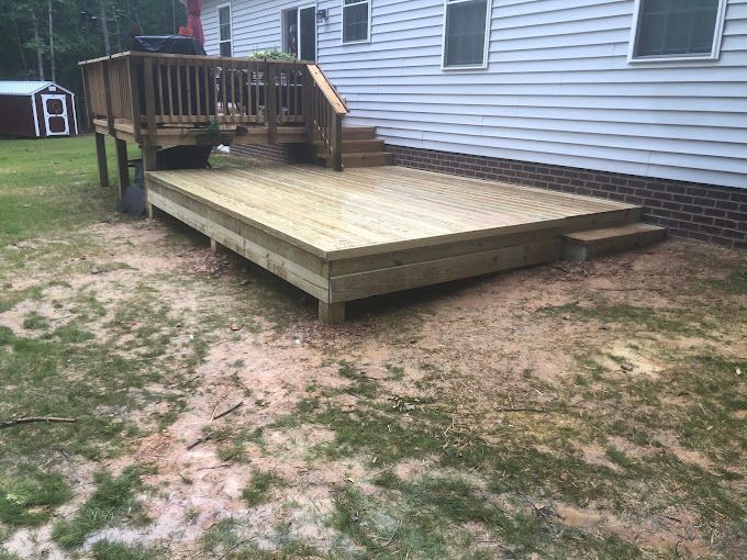 A wooden deck is sitting in front of a white house.