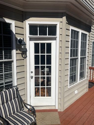 There is a patio door with a window above it and a chair on the deck.