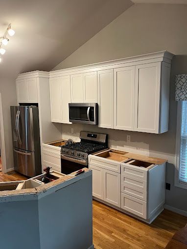 A kitchen with white cabinets and stainless steel appliances is being remodeled.