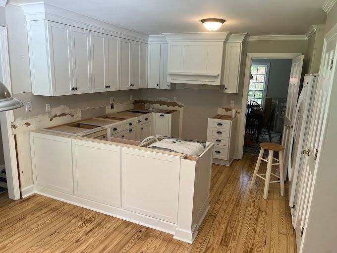 A kitchen with white cabinets and wooden floors is being remodeled.