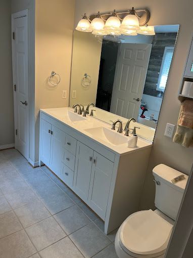 A bathroom with two sinks , a toilet and a mirror.