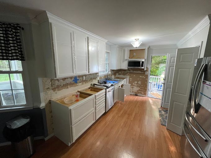 A kitchen with white cabinets and hardwood floors is being remodeled.