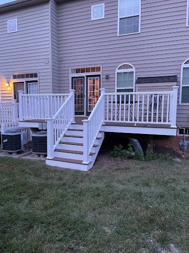 There is a deck with stairs leading up to it in front of a house.