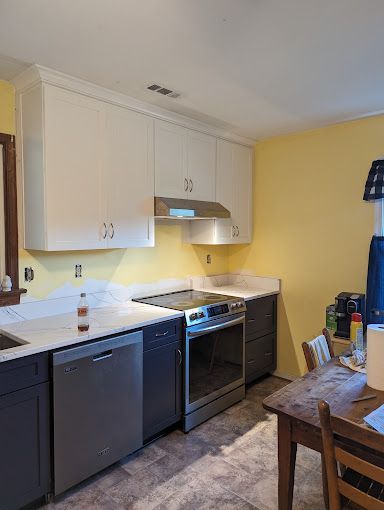A kitchen with a stove , dishwasher , sink , chairs and a table.
