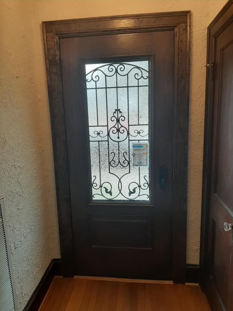 A door with a wrought iron design on it is in a hallway.