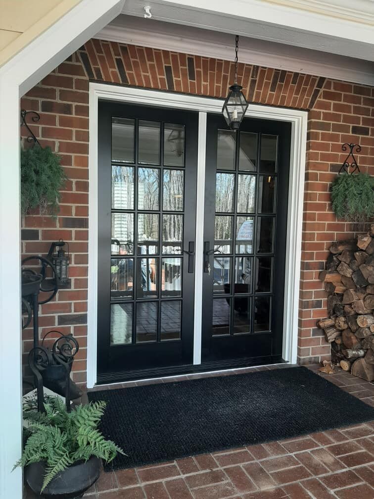 A brick building with a black door and a black mat