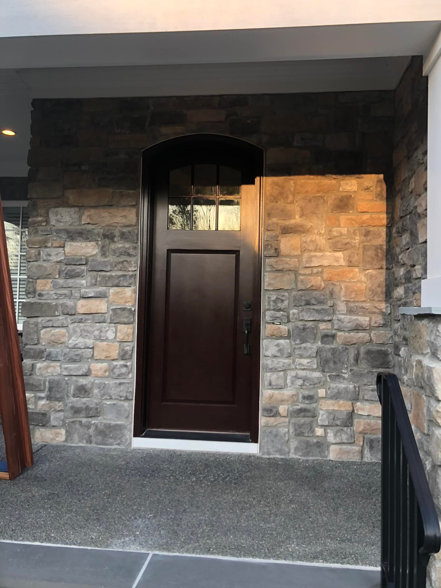 The front door of a house with a stone wall and a wooden door.