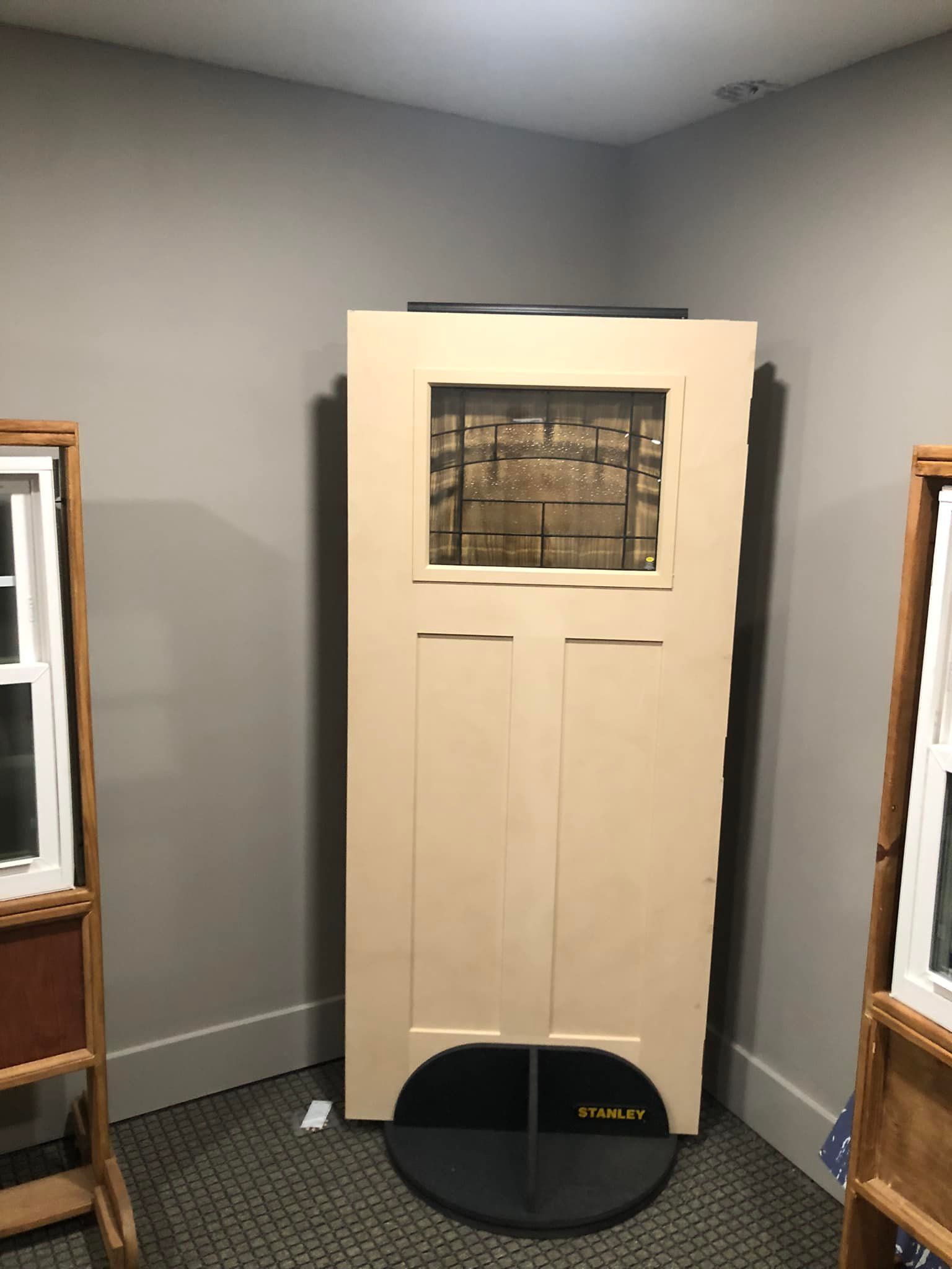 A door is sitting on a stand in a room next to a window.