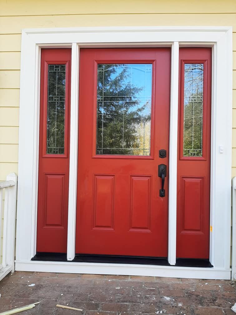 A red door with three windows on a yellow house