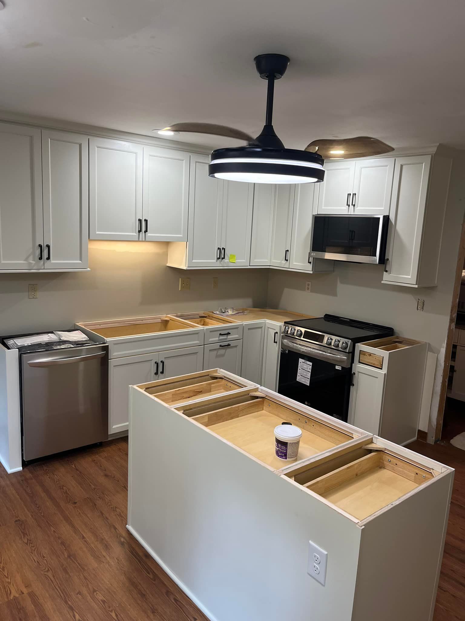 A kitchen with white cabinets and a ceiling fan.