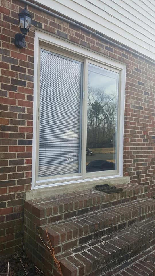 A sliding glass door is on the side of a brick house.