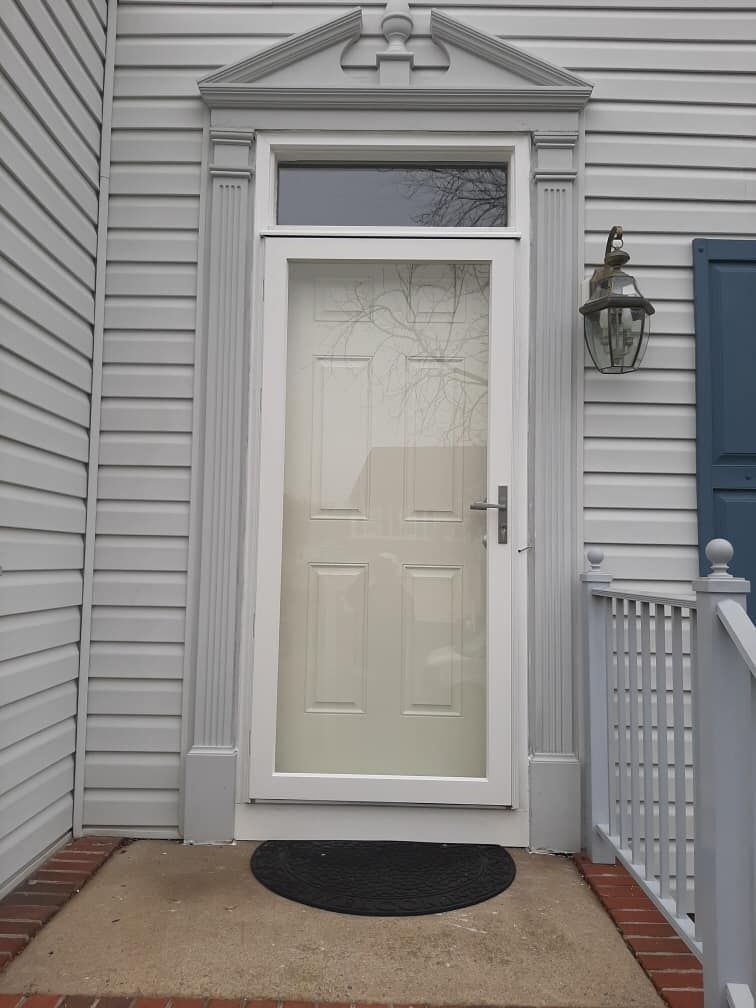 A white door with a glass window is on a white house
