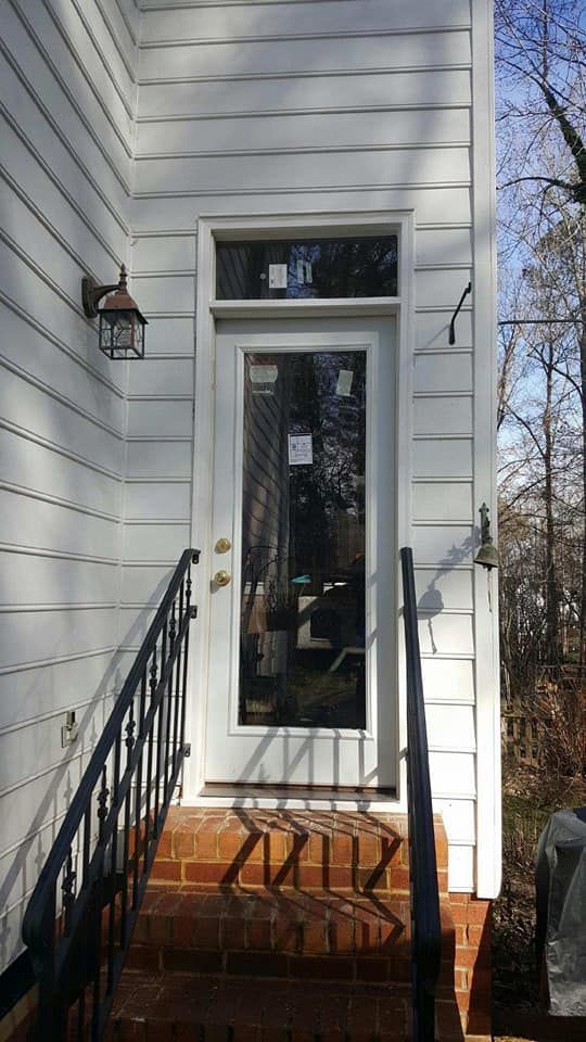 A white house with a glass door and stairs leading up to it.