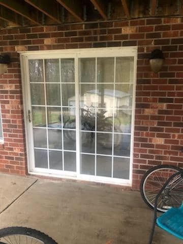 A sliding glass door is sitting on a patio next to a brick wall.