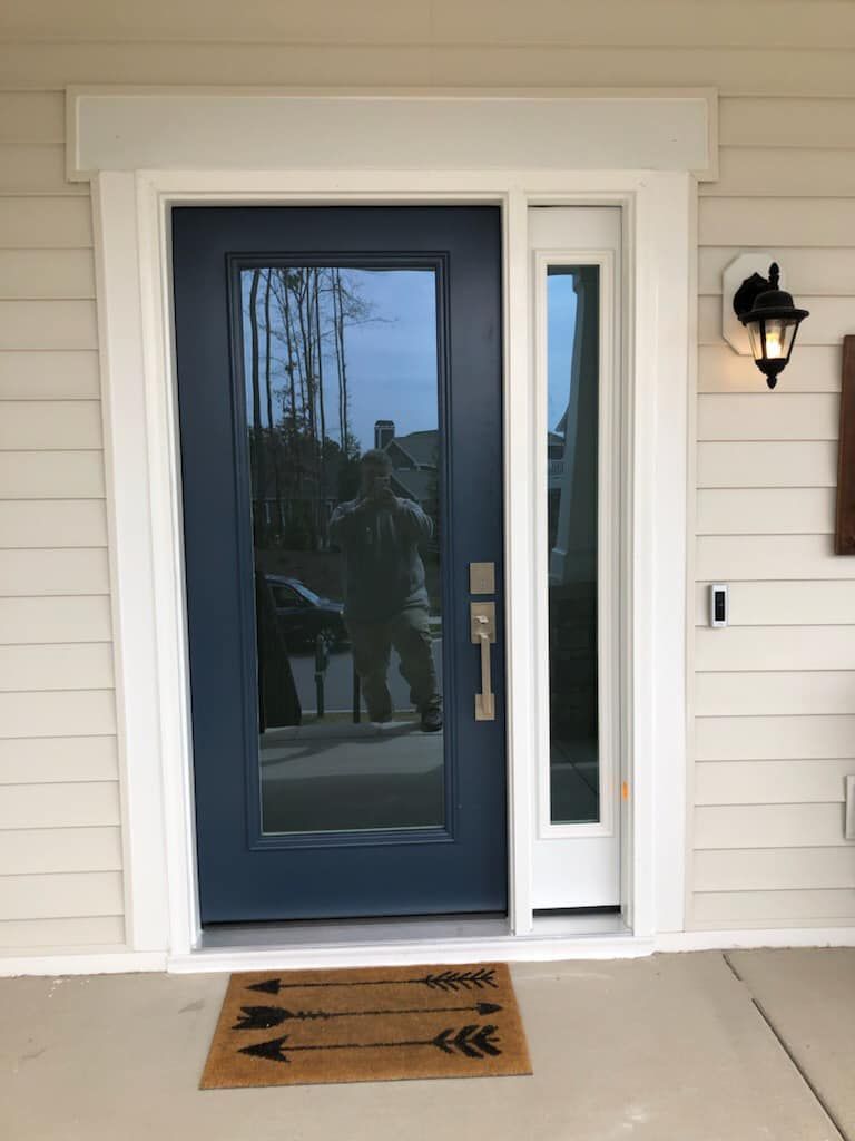 The front door of a house with a blue door and a white trim.