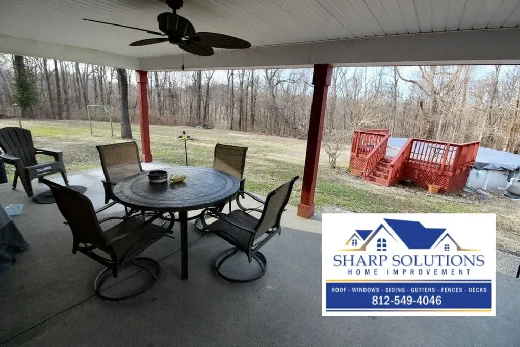 Covered patio with round table and chairs, ceiling fan, and yard beyond; Sharp Solutions logo in corner