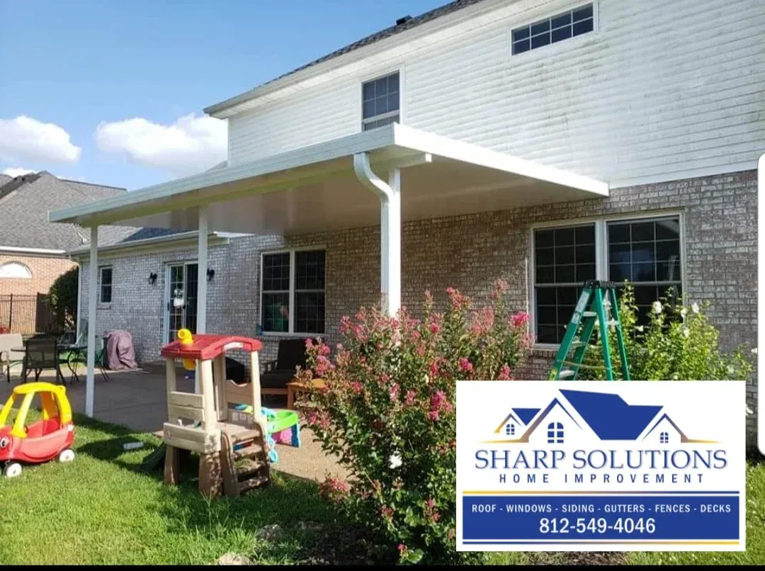 Residential house exterior with brick and white siding, patio, and children’s play equipment in the yard