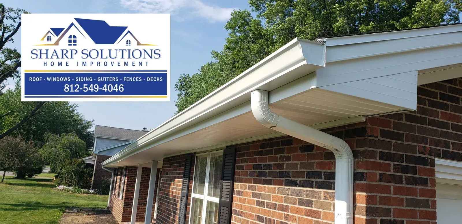 Sharp Solutions roofing sign above a brick house with white trim and blue sky