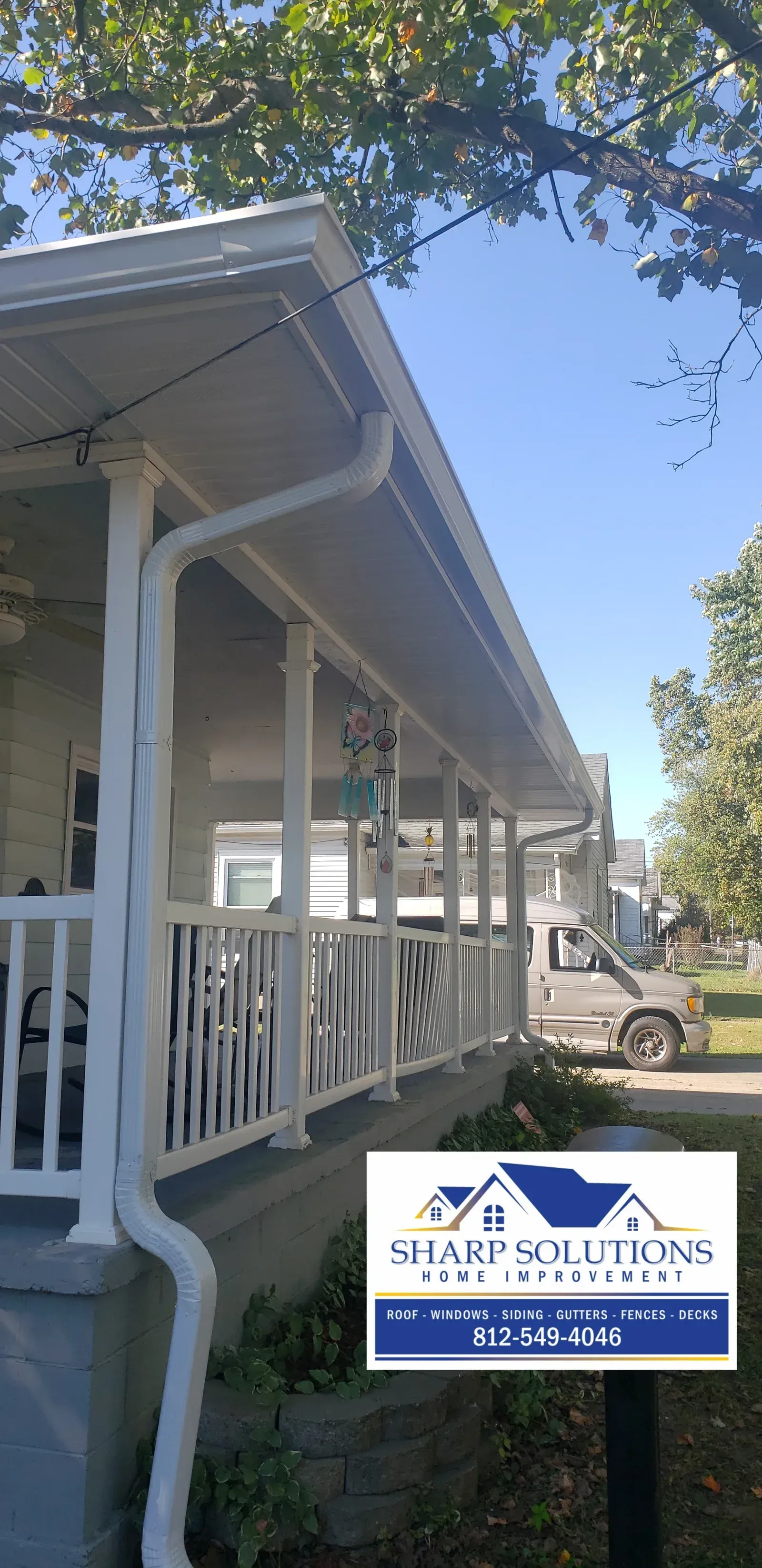 White porch and railing in front of a blue-and-white office sign under a clear sky