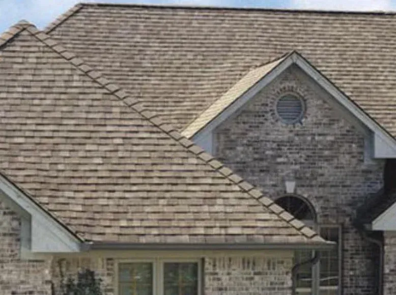 House roof with brown shingles and two round windows on a stone gable.