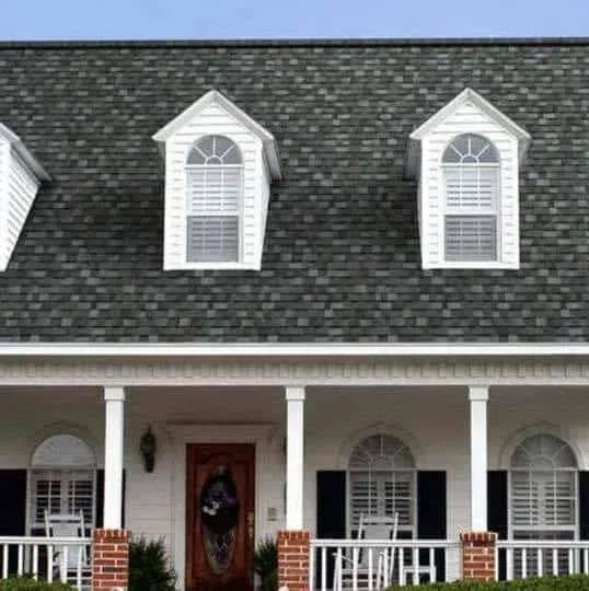 Suburban house with gray shingle roof, white trim, dormer windows, and a red front door