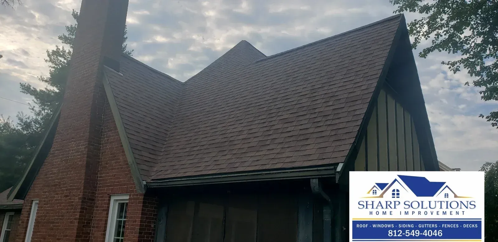 House roof and chimney under a cloudy sky, with a Sharp Solutions logo in the bottom right.