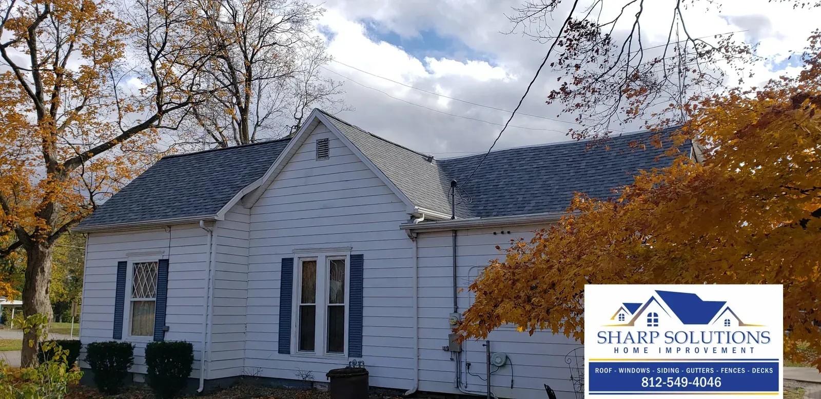 White house with gray roof and autumn trees, with a Shady Solutions logo in the corner