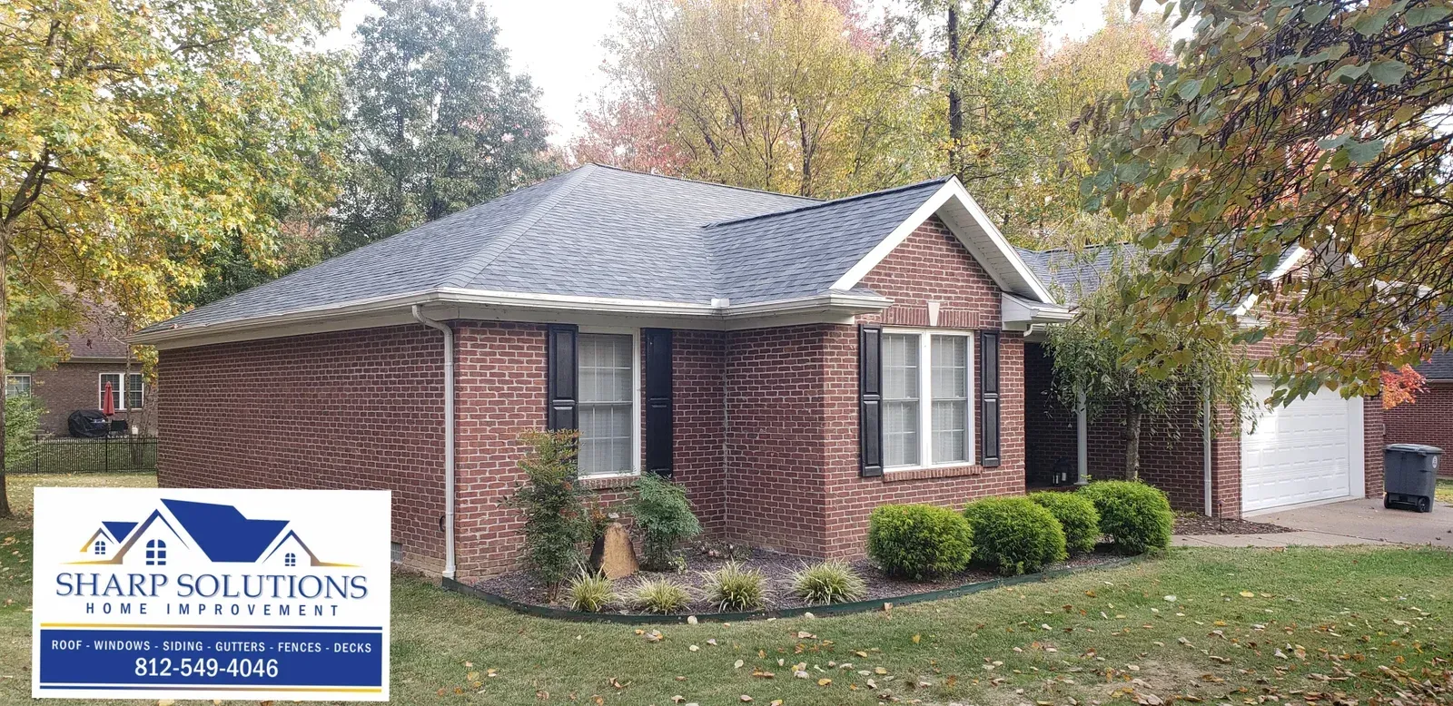 Brick house with gray roof and a “Shark Solutions” sign in the front yard