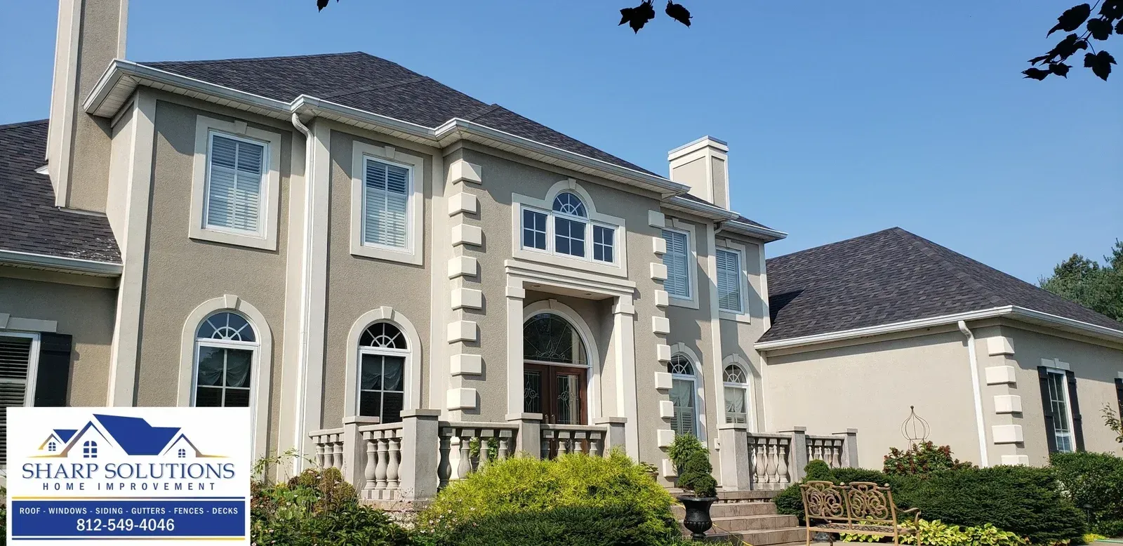 Luxury two-story beige house with arched windows and a landscaped front yard under a blue sky