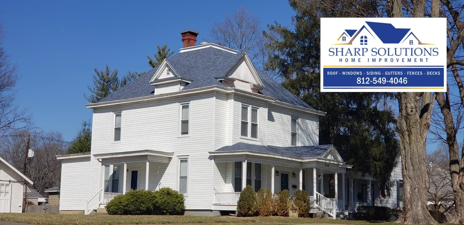 White two-story house with porch and a Shapik Solutions roof service sign in the upper right.