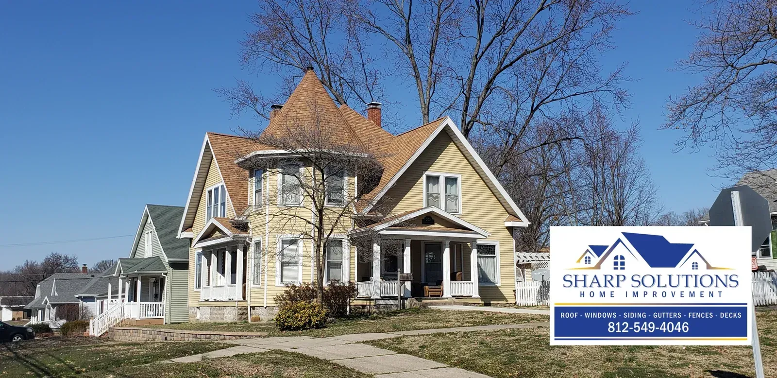 Victorian-style house with a real estate sign in front under a blue sky.