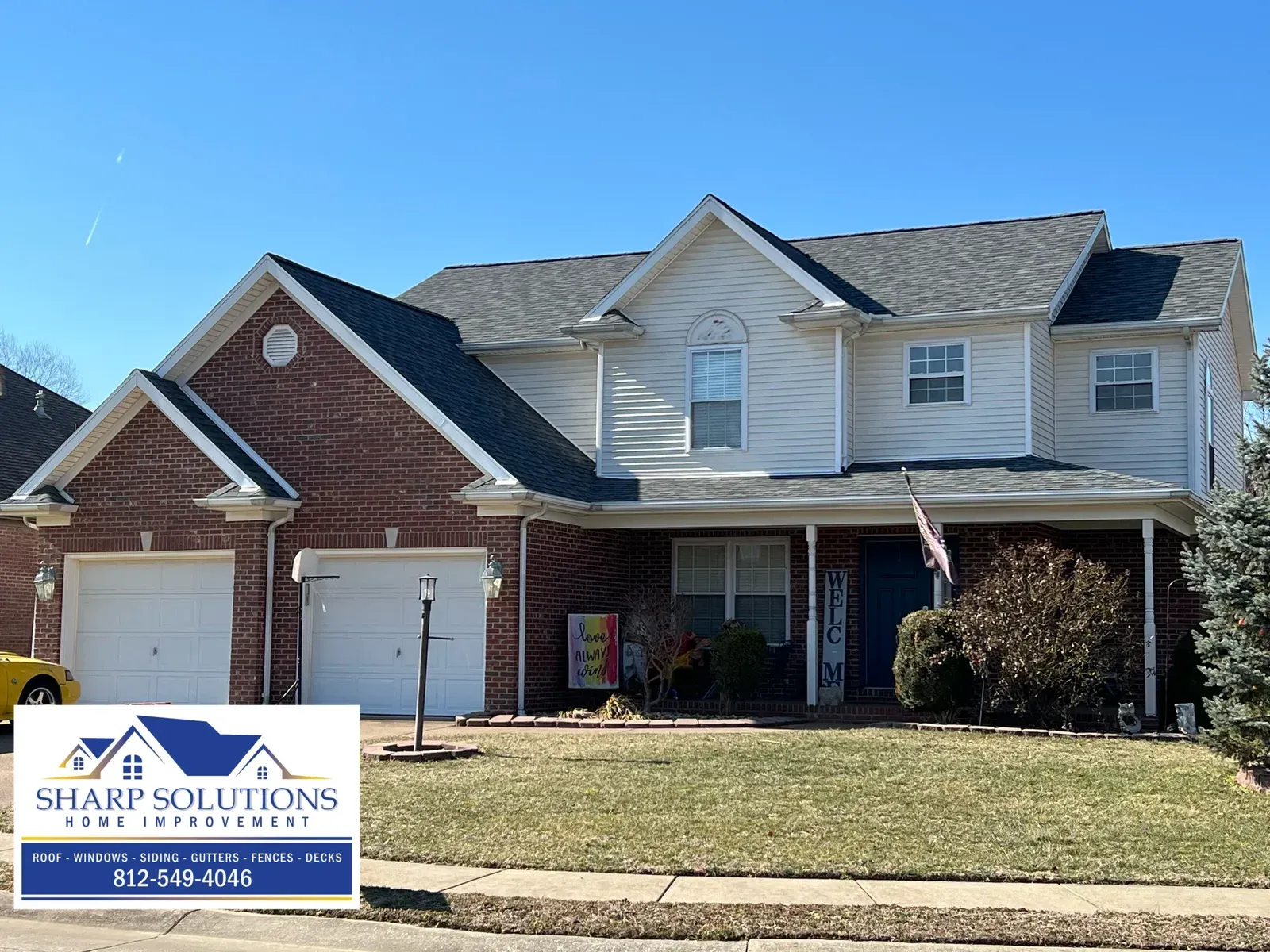 Two-story brick and siding suburban house with a front porch and garage on a sunny day