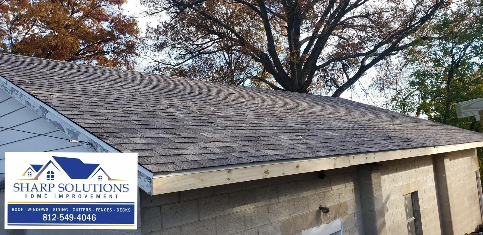 Roof with gray shingles and a Sharp Solutions Roofing sign in the lower left corner