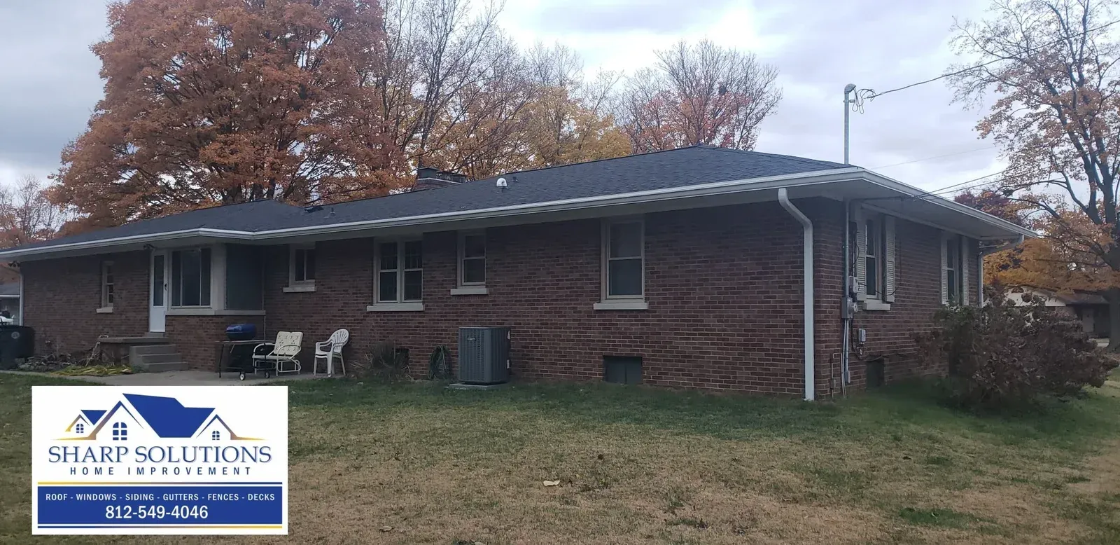 Single-story brick building with a sign, leafless trees, and a gray roof in a suburban setting