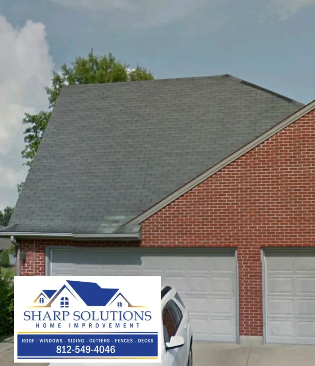 Brick house with gray roof and garage, featuring a Sharp Solutions roofing sign in the front yard