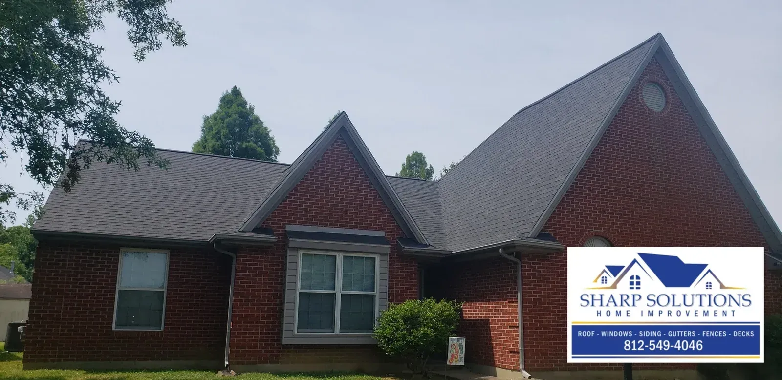 Brick house with dark shingle roof and a Sharp Solutions sign in the front yard